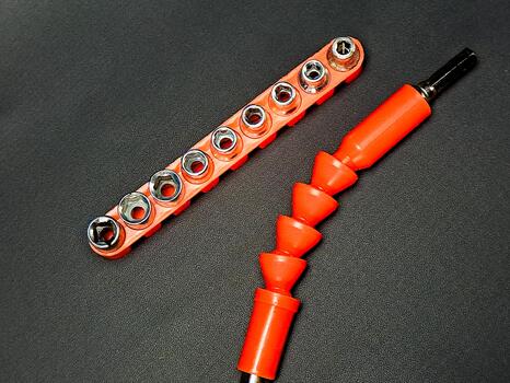 Orange socket set and flexible extension bar on dark texture offer tool versatility and utility. photo