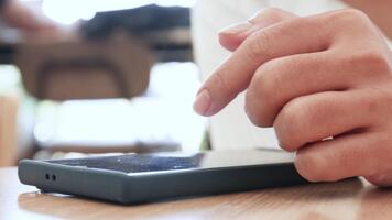 mano utilizzando smartphone, avvicinamento di un' persona mano interagendo con un' smartphone su un' di legno tavolo, mostrando toccare gesti e un' calma interno atmosfera video