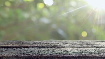 vecchio di legno tavolo con morbido luce del sole e naturale bokeh sfondo. Perfetto come un' fondale per Prodotto Schermo, presentazioni, o rilassante natura temi video