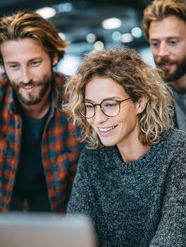 Coworkers collaborating and smiling while working on laptop photo