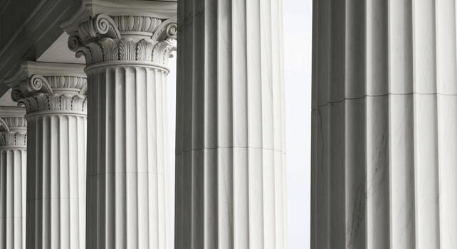 A row of white columns in front of a building photo