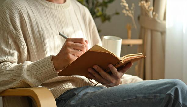 A man is sitting in a chair and holding a notebook photo