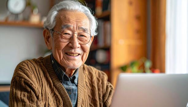 An older man is smiling while using a laptop photo