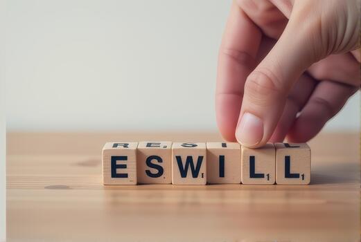 Hand rearranges wooden letter tiles on table, forming word WILL with playful touch. scene conveys creativity and focus, highlighting tactile interaction with tiles photo