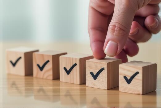 Hand arranging wooden blocks with check marks on reflective surface, symbolizing organization and completion. scene conveys sense of achievement and order photo