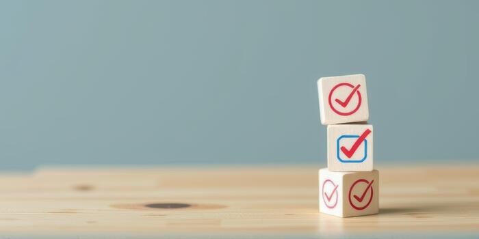 Stacked wooden blocks with check marks symbolize success and completion on wooden table against blue background. minimalist design conveys sense of achievement photo