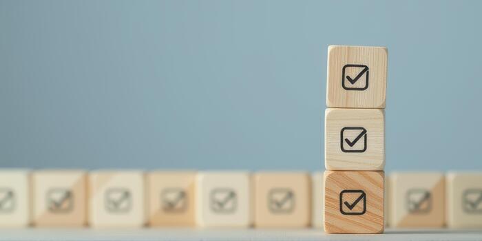 Wooden blocks with check marks are stacked against soft blue background, symbolizing completion and organization. arrangement conveys sense of achievement and order photo