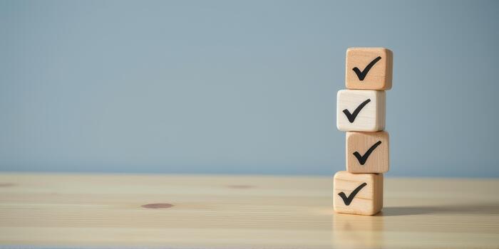 Wooden blocks with check marks stacked on wooden table, symbolizing completion and success. background is plain blue, creating calm and focused atmosphere photo