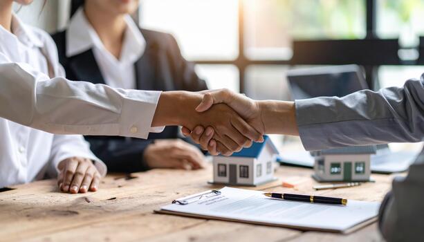 Professional handshake between business partners modern office setting, symbolizing agreement and collaboration. scene includes miniature houses and documents, reflecting real estate transactions photo