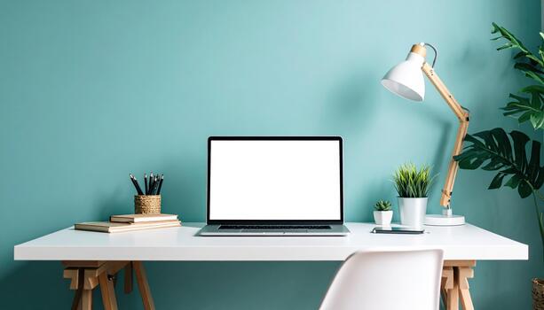 Modern workspace with clean white desk, open laptop, potted plants, and stylish desk lamp against teal wall creates calm and organized environment perfect for productivity and focus photo