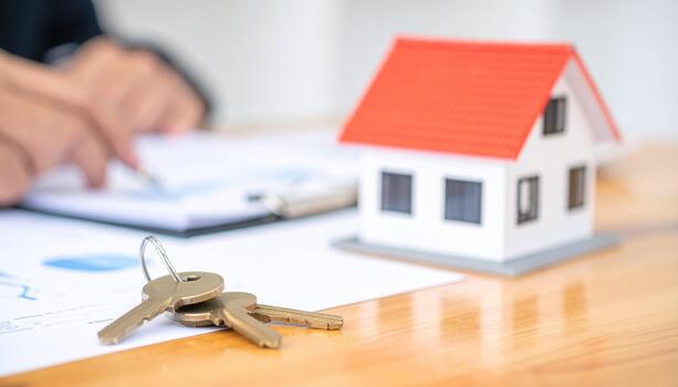 Real estate agent signing documents with keys and house model photo
