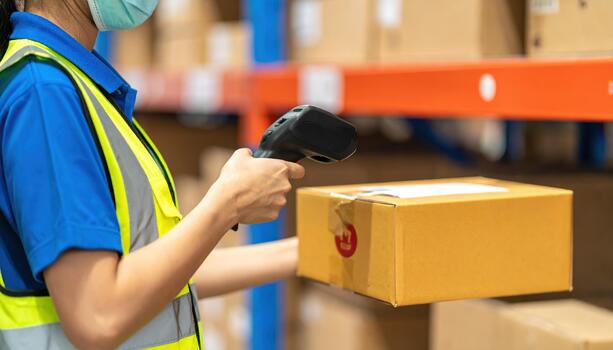 Warehouse worker barcode scanner box inventory logistics shipping storage safety vest mask efficient process in warehouse with worker scanning barcode on box for inventory management and shipping photo
