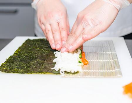 A person cutting up a sushi roll photo