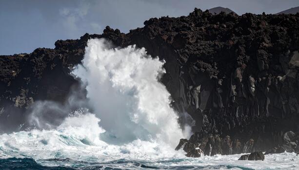 Ocean wave crashing volcanic rock coastline with dramatic splash and dark rugged lava cliff under cloudy sky photo
