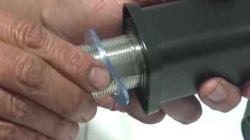 närbild av hand justeras en mekanisk komponent på en mörk bakgrund med metall detaljer och precision utförande video