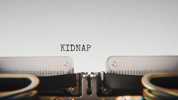 Old mechanical typewriter typing Kidnapping in a close up view, with metal letters striking the white paper. video