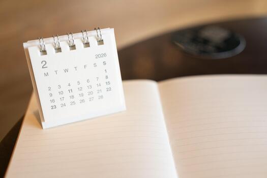 Mini Desk Calendar Showing February 2026 on Open Notebook, Symbolizing a Fresh Start and Business Planning. business planning, goal setting, time management, or setting a new schedule. photo