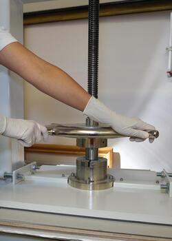 Hands in protective gloves rotate the handle of the screw press. Paper pressing and straightening, bookbinding workshop, vertical frame. photo