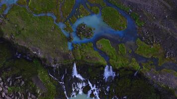 zumbido parte superior abajo ver muestra lechoso turquesa aguanieve en Islandia, trenzado canales, musgo islotes, y cascadas terminado basalto acantilados en suave difuso luz, patrones y movimiento video