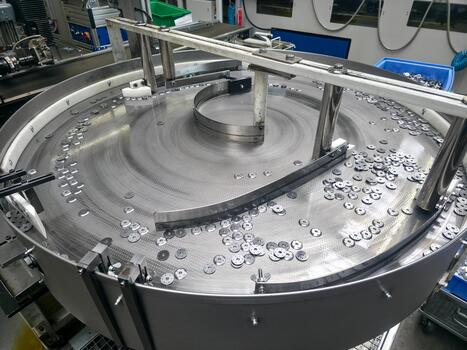 Washers in rotary feeder bowl align and proceed through assembly line automation photo