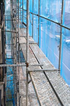 Scaffolding structure providing temporary access with platforms and protective netting for a building renovation project photo
