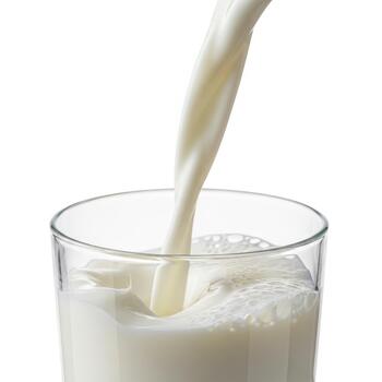 Milk being poured into a glass, creating a frothy cascade, isolated on white background photo