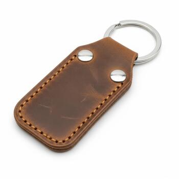 Rustic brown leather keychain with metal ring and rivets, isolated on white background photo