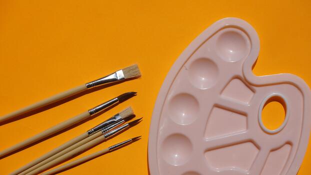 Paint palette and brushes on a yellow background, top view photo