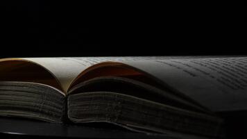 sidor skriven av en öppen bok vändning med svart bakgrund, rotation. video