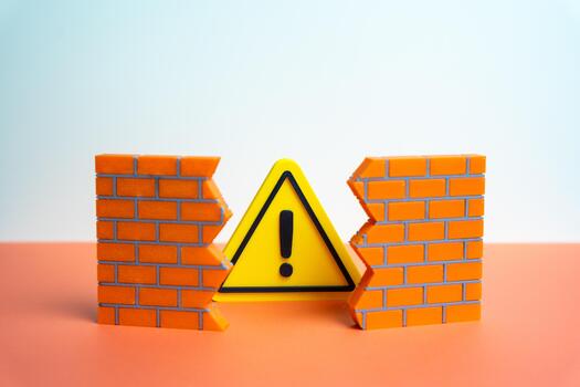 A warning sign bursts through a hole in the wall. A problem that destroys integrity. A warning about an error or malfunction that cannot be ignored for long. Cybersecurity, business risk assessment photo
