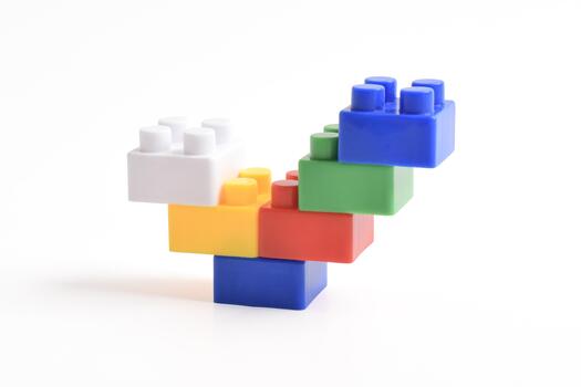 Colorful building blocks stacked precariously on a white background, creating a playful structure. photo