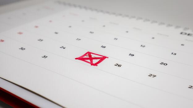 A close-up of a calendar page with the number 25 crossed out with a red marker. Other dates are visible around it, but the focus is on the marked photo