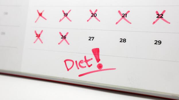 A calendar with the Diet and a red exclamation point, with some past dates crossed out, symbolizes commitment to health goals. photo