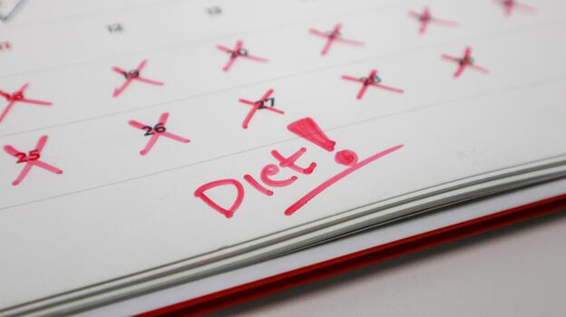 A calendar with the word Diet and a red exclamation point, with some past dates crossed out photo