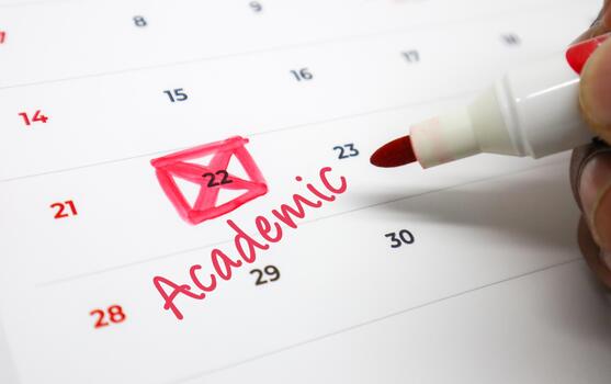 Hand Marking Academic Deadlines and Important Dates on a Calendar with a Red Marker, Symbolizing Educational Planning and Scheduling photo
