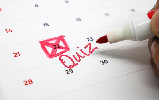 Red marker hand annotates a personal calendar, highlighting a quiz date and checkmark for upcoming academic or professional assessment scheduling photo