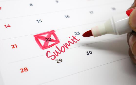 A hand marking an urgent Submit deadline with a red pen and envelope icon on a calendar, emphasizing important due dates for tasks and projects photo