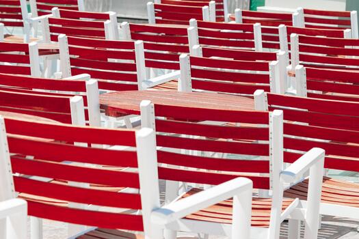 Rows of red wooden chairs with white frames arranged outdoors in sunlight, backdrop as minimal style graphic pattern. Concept of order, repetition, structure and summer leisure. photo