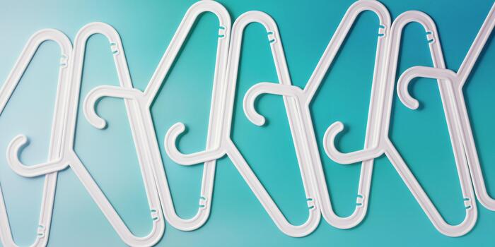 White Clothes hangers as creative minimal composition on teal gradient background, Plastic racks creating modern and geometric aesthetic, top view banner, creative photo, smooth lines pattern photo