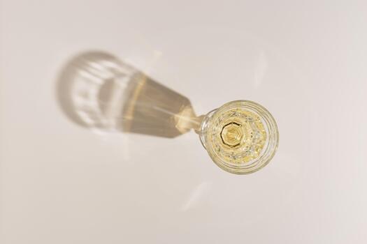 Top view of wineglass with white wine with beautiful shadows and glare at sunlight, summer alcohol drink background beige monochrome color, creative aesthetic view of wine glass goblets style photo