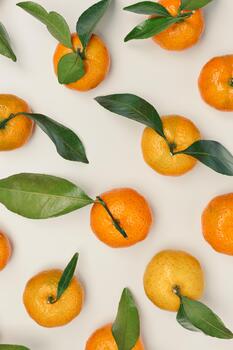 Fresh juicy orange yellow tangerines as minimal flat lay pattern, Citrus fruits with green leaves on beige table background. Still life creative trend pattern of mandarin oranges overhead, above photo