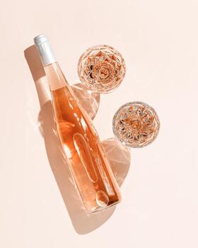 Glasses of rose wine on pink background with shadows from sunlight. Minimal Top view Vintage wineglasses and bottle, sparkling alcohol drink above view with caustics effect from hard light, copyspace photo