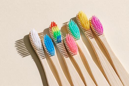 Eco friendly Bamboo toothbrushes with colored bristles at sunlight with dark shadows on beige background. Sustainable living concepts, minimal style aesthetic photo, top view set wooden brushes photo