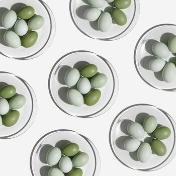 Pattern with Easter eggs green gradient color on glass plate with Shadow at sunlight, light background. Chicken eggs on table, traditional food and symbol of Easter, top view, minimal style photo