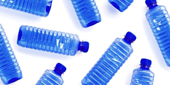 Pattern of blue plastic bottles isolated on white, top view empty plastic bottle for water half litre, minimal style design. Pollution, plastic garbage, environmental protection concept photo