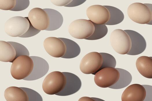 Easter eggs monochrome pattern with gradient colored eggshell, hard Shadow at sunlight, beige background. Chicken eggs layout, top view, minimal flat lay, holiday food still life photo, trend photo