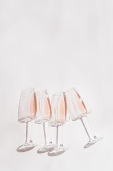 Rose wine in stemmed glasses, minimal style still life, top view rose champagne sparkling wine with sunlight and shadows. Summer light alcoholic drink on white background, copy space photo