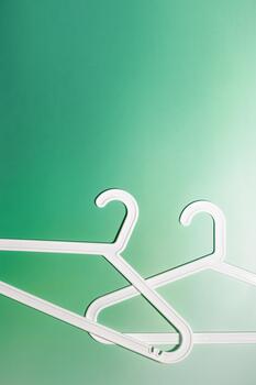 Top view minimal style photo of white plastic hangers with hooks on white green background. Flatlay with Clothes rack for hanging garments. Minimal trend image, lifestyle or interior design content