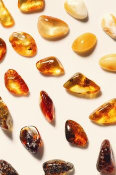 Minimal trend pattern from amber stones on beige background, stone yellow beige gradient color. Natural gemstone healing crystal. Top view monochrome vertical fon. Nature gems, pieces resin. photo