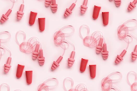 Red earplugs as minimal trend pattern, reusable silicone and rubber ear plug on cord against noise, protect hear, for swim, sleep, rest. Creative aesthetic flat lay, above view, pastel tones photo